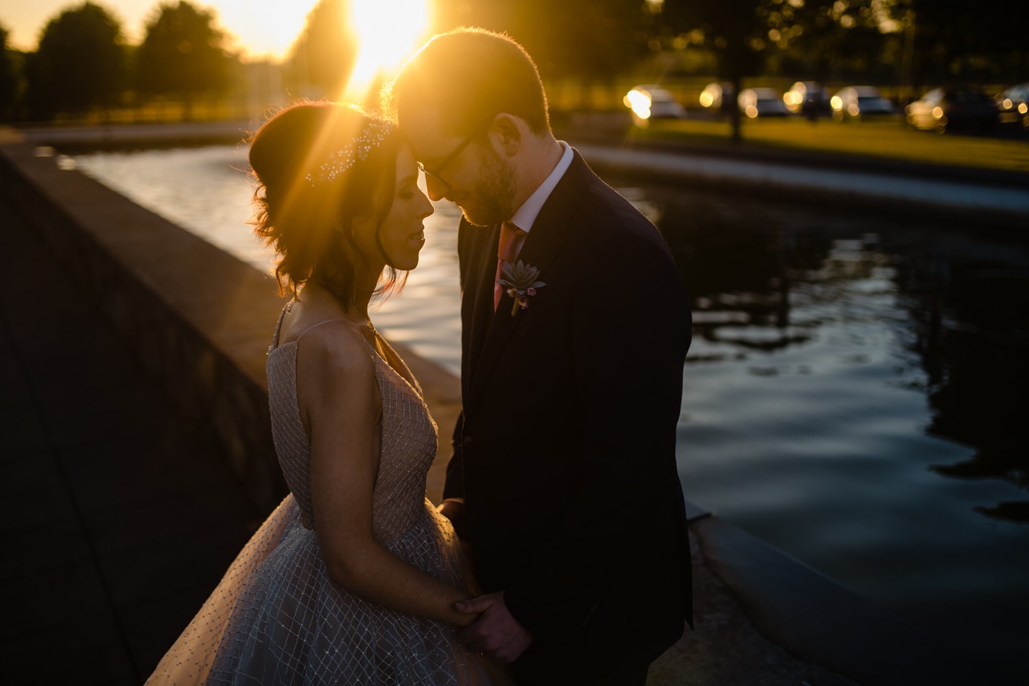 Couple under sunset at wedding at Johnstone Estate by a water feature.