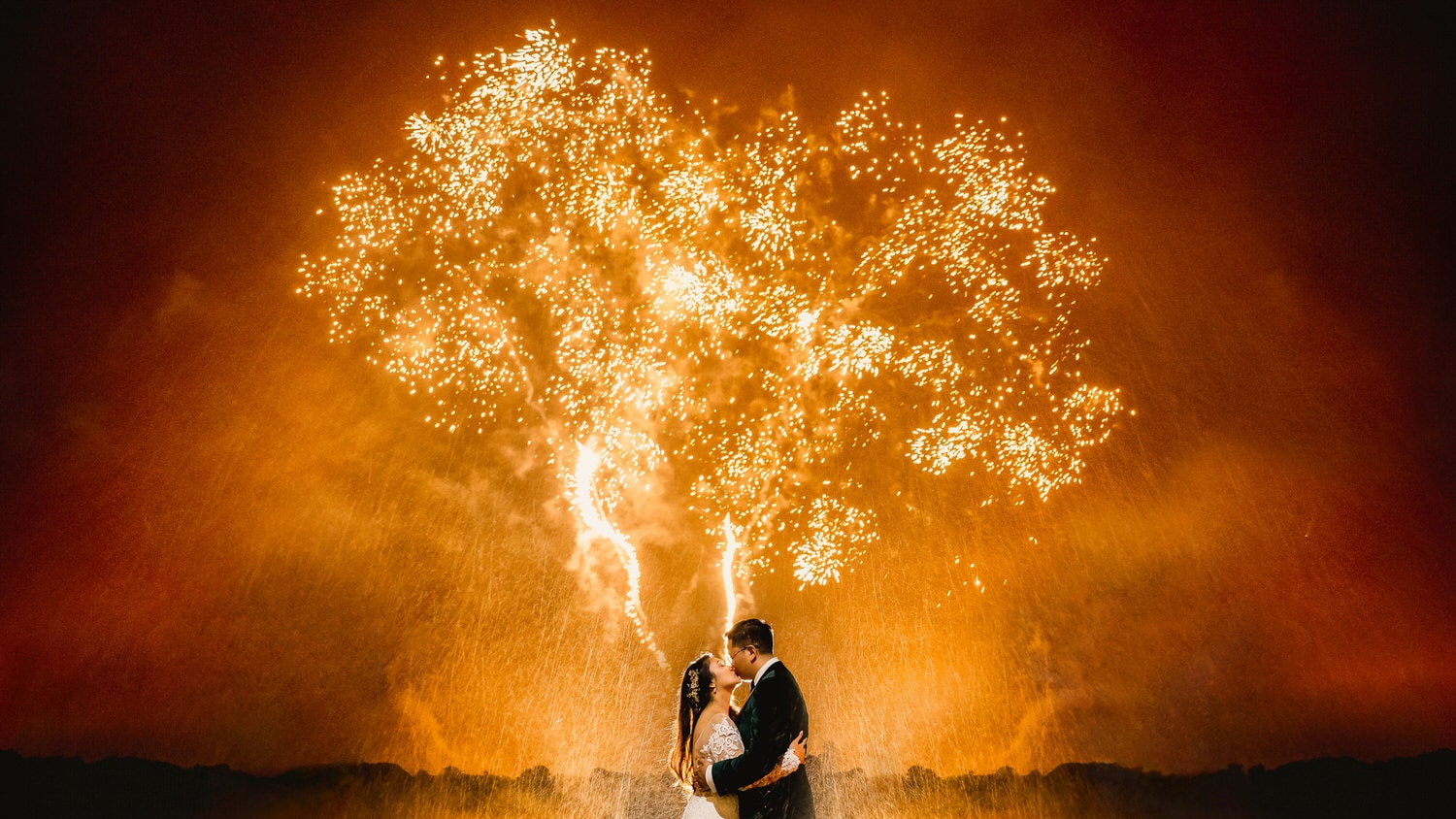 Wedding couple kissing under dramatic firework shaped like a heart at Luttrellstown Castle. 