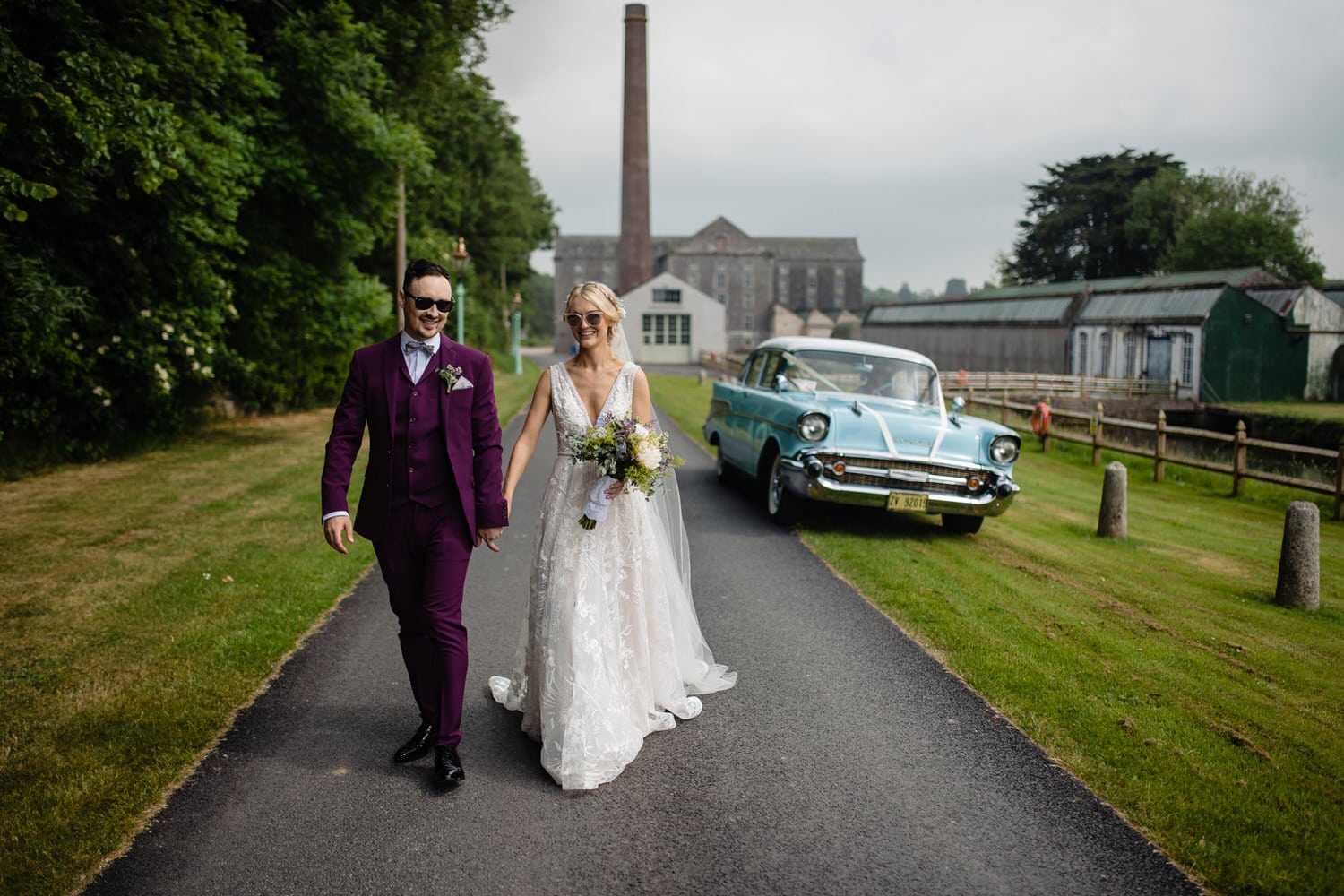 Stylish wedding couple walking in front of The Millhouse with cool blue vintage car. 
